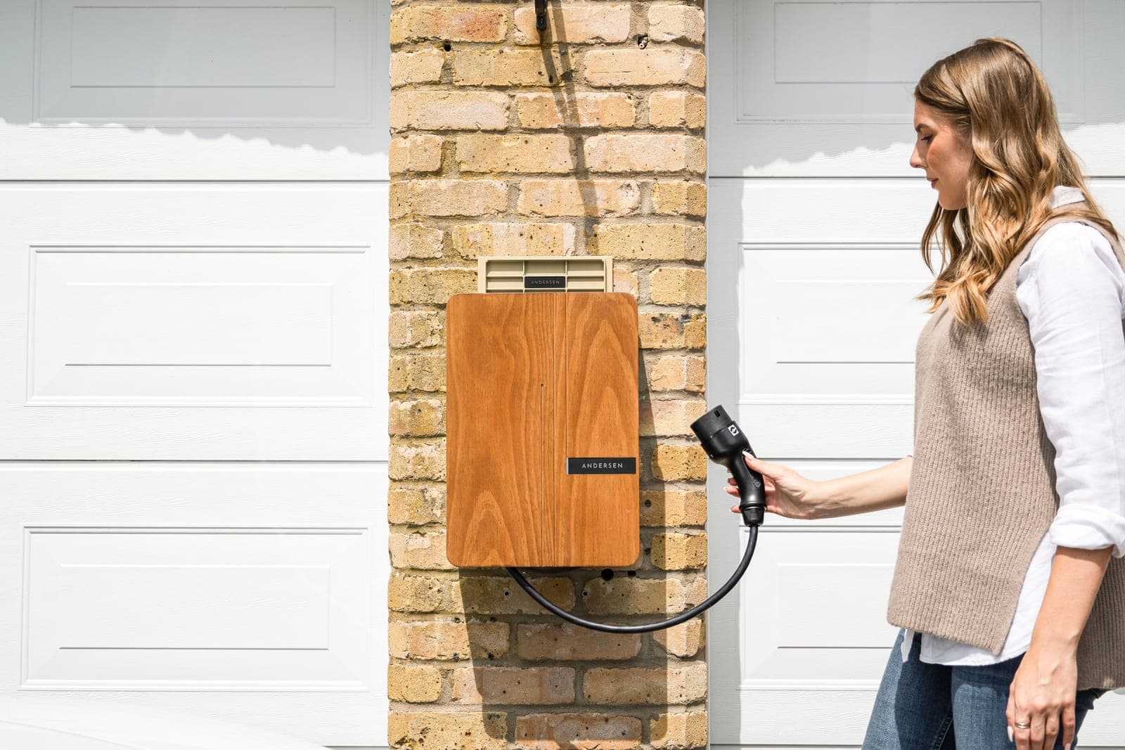 An electric car charging from a wall-mounted Level 2 charger at a modern home